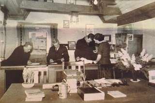 Informatrice helpt klanten aan de balie anno 1939